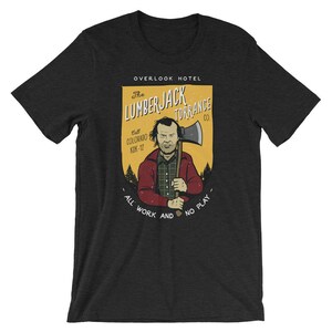 Może przedstawiać: Szary t-shirt z ż&oacute;łto-pomarańczową grafiką przedstawiającą mężczyznę trzymającego siekierę. Grafika zawiera napis "The Lumberjack Torrance Co." i "All Work and No Play".