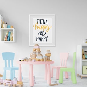 May include: A pink children's table and chairs set with a white frame and a motivational quote on the wall that reads "Think happy, be happy".