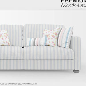 Könnte beinhalten: Ein weißes, gestreiftes Sofa mit vier Kissen. Zwei Kissen haben ein Blumenmuster, eines ein gestreiftes Muster und eines ein einfarbiges rosa und graues Muster. Das Sofa steht auf einem weißen Hintergrund.