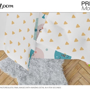 May include: A white bed sheet with a yellow triangle pattern and a blue and pink cartoon design. The sheet is folded over a white fluffy rug on a wooden floor.