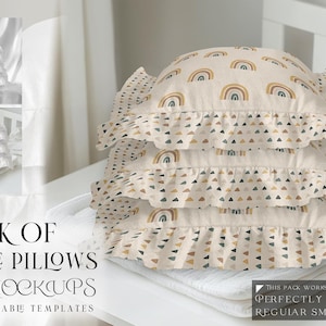 May include: A stack of three ruffle pillows with a rainbow and geometric pattern. The pillows are beige with brown, yellow, and blue accents. The pillows are arranged on a white surface.