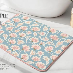 May include: A blue and pink floral bath mat with a pink border. The mat has a repeating pattern of pink flowers on a light blue background.