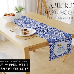 Puede incluir: Un camino de mesa azul y blanco con un patrón floral y un diseño de pájaro. El camino de mesa está sobre una mesa de madera con un plato y un postre encima. El texto "TABLE RUNNER PSD MOCKUPS 12 CUSTOMIZABLE PSD TEMPLATES" está en la parte superior de la imagen.
