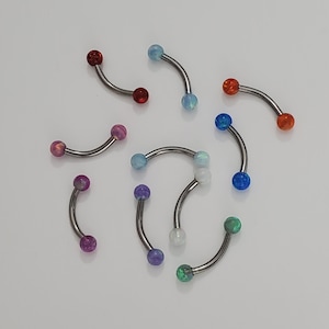 May include: A collection of nine curved barbell body jewelry pieces with opal-like balls in various colors, including red, blue, green, purple, and white.