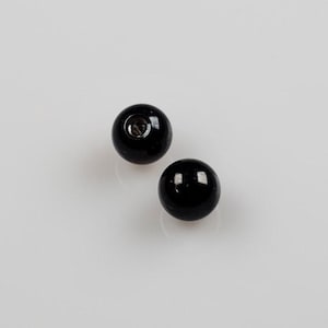 May include: Two black round beads with a small hole in the center.