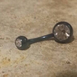 May include: A black belly button ring with two clear crystal stones.