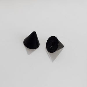 May include: Two black cone-shaped metal studs with a threaded base.