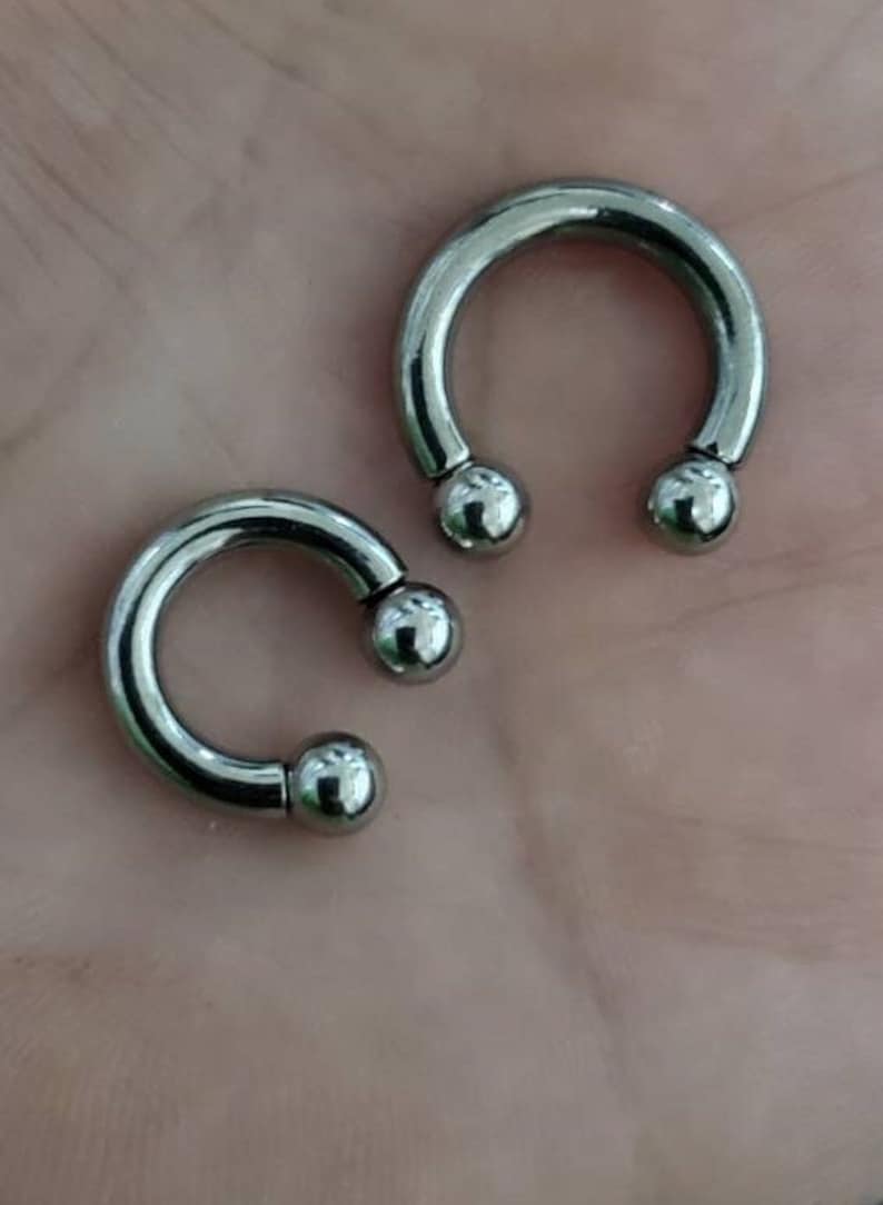 May include: Two silver circular barbell piercings with rounded ends.