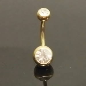 May include: Gold belly button ring with two clear round stones.