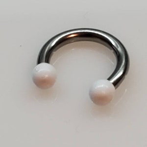 May include: A silver circular barbell with white balls on each end.