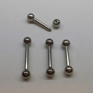 May include: Four silver barbell body piercing jewelry pieces with ball ends. The barbells are arranged in a row, with the top barbell slightly offset to the right.