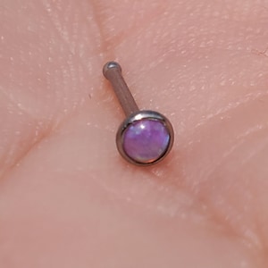 May include: A silver nose ring with a small, round, iridescent purple opal gemstone.