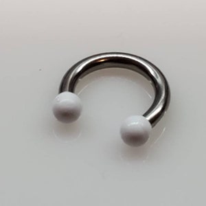 May include: A silver horseshoe-shaped body piercing with white balls on each end.