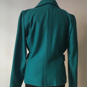 May include: Teal blazer with long sleeves and a single button closure. The blazer has a fitted silhouette and a belt at the waist.