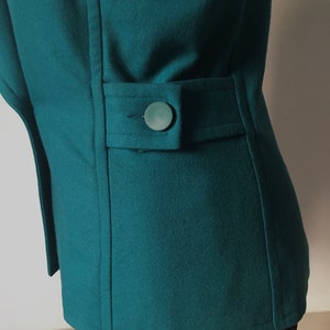May include: A teal blue blazer with a single button on the back pocket.