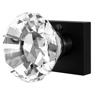 May include: A faceted crystal door knob with a black square backplate. The crystal knob is large and clear, reflecting light. The black backplate has a small, round accent. This door hardware is designed for interior doors.