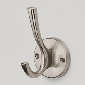 May include: A brushed nickel wall hook with a curved design. The hook is mounted on a circular base with two screw holes. The metal finish has a matte appearance, suitable for hanging coats or other items.