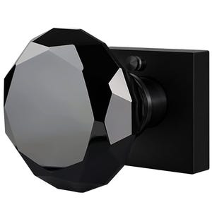 May include: A black door knob with a faceted, gem-like design. The knob is mounted on a square, matte black backplate. The faceted surface reflects light, creating a sparkling effect. A modern, elegant hardware piece.