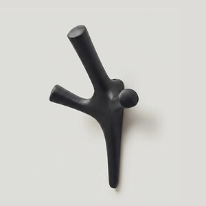 May include: A matte black wall hook with a branching, organic silhouette featuring three distinct prongs of varying lengths and a rounded central base. The design resembles a stylized tree limb or coral structure with a smooth, uniform finish.