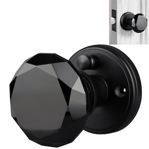 May include: Black door knob with a faceted glass design. The knob is attached to a black round base plate.