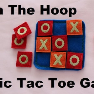 Peut inclure: Un jeu de tic-tac-toe en feutre avec des carrés orange et rouge. Les carrés ont des X et des O brodés. Le jeu est sur un fond bleu. "In The Hoop Tic Tac Toe Game" est écrit sous le jeu.