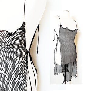 May include: Black mesh slip dress with a loose fit and a scalloped neckline. The dress has adjustable straps and a tie at the side.