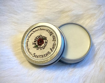 Puede incluir: Una pequeña lata de plata con una tapa blanca. La lata está etiquetada con "Soothing Anti-Itch Balm" y "Calming for Eczema, Psoriasis, Rashes & Irritations".
