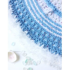 May include: A close-up of a crocheted hat in shades of blue and white, with a fluffy white trim. The hat has a textured design with sparkling accents. The text "The Lonely Sea" is visible at the bottom.