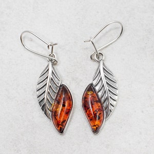 The marquise amber cabochon is set in a solid sterling silver frame, providing a stunning contrast that catches the eye. The leaf design is intricate and delicate, creating a beautiful and unique look that is sure to turn heads.