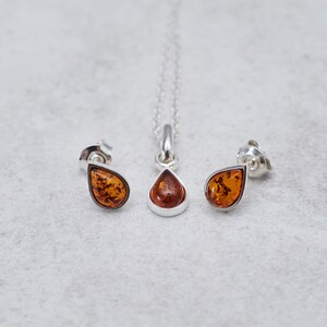Puede incluir: Un conjunto de collar y pendientes de plata con piedras de &aacute;mbar en forma de l&aacute;grima.
