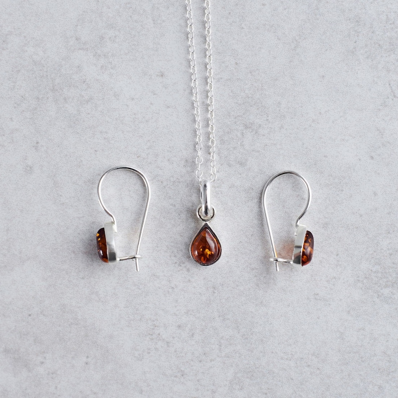 Puede incluir: Un conjunto de pendientes y un collar con colgante de &aacute;mbar. Los pendientes y el colgante tienen forma de l&aacute;grima y tienen un engaste de plata.