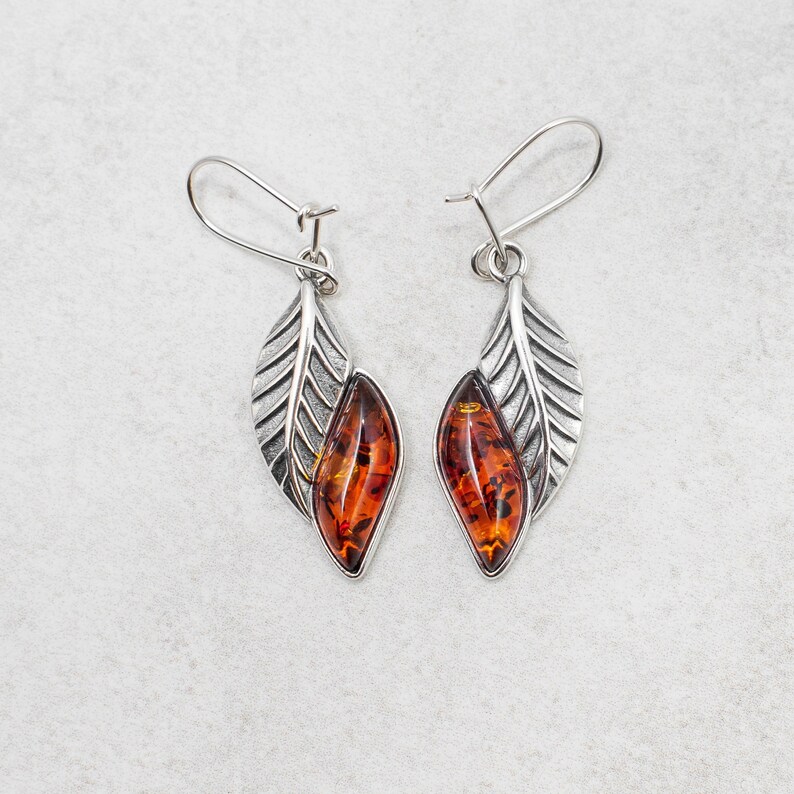 The marquise amber cabochon is set in a solid sterling silver frame, providing a stunning contrast that catches the eye. The leaf design is intricate and delicate, creating a beautiful and unique look that is sure to turn heads.