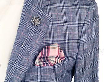 May include: A blue blazer with a pink and white checked pattern. The blazer has a pocket square in a pink and white checked pattern and a silver pin in the shape of a flower.