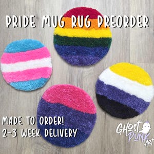 Puede incluir: Cuatro posavasos redondos con diseños de banderas del Orgullo. Uno presenta un arcoíris, otro la bandera transgénero, un tercero la bandera bisexual y el último la bandera no binaria. Texto: "Pride Mug Rug Preorder" y "Made to Order! 2-3 Week Delivery."