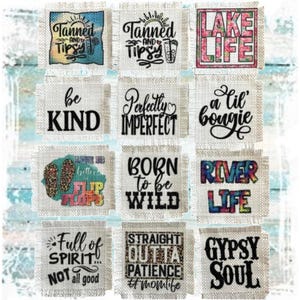 May include: A collection of square coasters with various phrases and graphics. The coasters feature text like "Tanned and Tipsy," "Lake Life," "Be Kind," and "Born to be Wild." The designs include beach-themed elements and floral patterns.