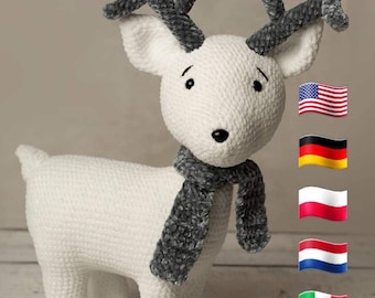 Puede incluir: Un reno de crochet blanco con cuernos grises y una bufanda gris. El reno está de pie sobre una superficie de madera. La imagen incluye banderas de los Estados Unidos, Alemania, Polonia, Países Bajos e Italia. El texto "AniAmi Creations" es visible en la parte inferior de la imagen.