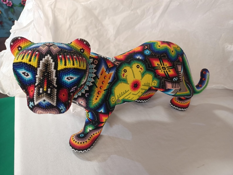 May include: A colorful beaded jaguar figurine with intricate geometric patterns in shades of blue, yellow, red, green, and black.