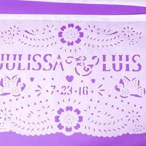 Puede incluir: Bandera de papel blanco con intrincados dise&ntilde;os recortados, incluyendo flores, p&aacute;jaros y corazones. La bandera dice "Julissa & Luis 7.23.16".