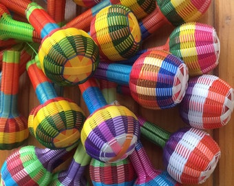 May include: A group of colorful woven maracas with different colored stripes and patterns. The maracas are made of plastic and have a round shape.