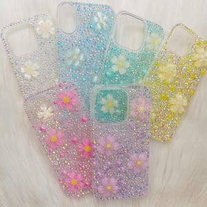 May include: Six clear phone cases with a sparkly, iridescent finish. Each case features a different colour and has a floral design with 3D flowers.