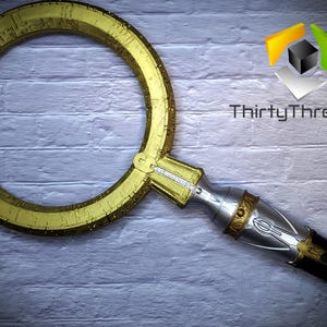 May include: A gold-colored, circular prop with markings and a silver handle. The handle has a decorative design and a black end.
