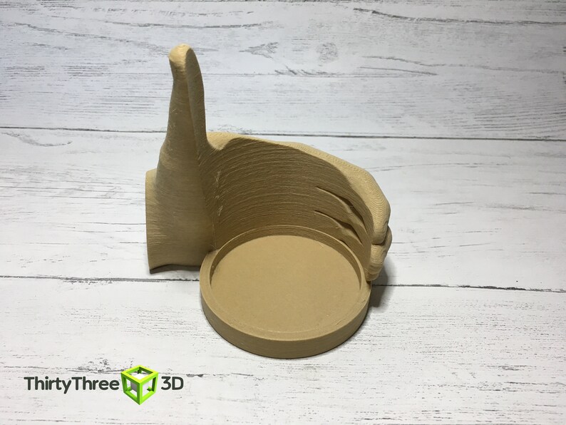 May include: A 3D printed beige thumbs up hand with a round, hollowed out center. The hand is giving a thumbs up gesture.