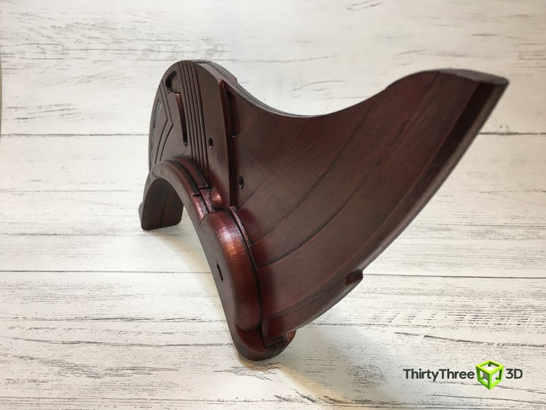 May include: A dark red wooden decorative piece with a curved shape and intricate details. The piece has a smooth, polished finish and appears to be handcrafted.
