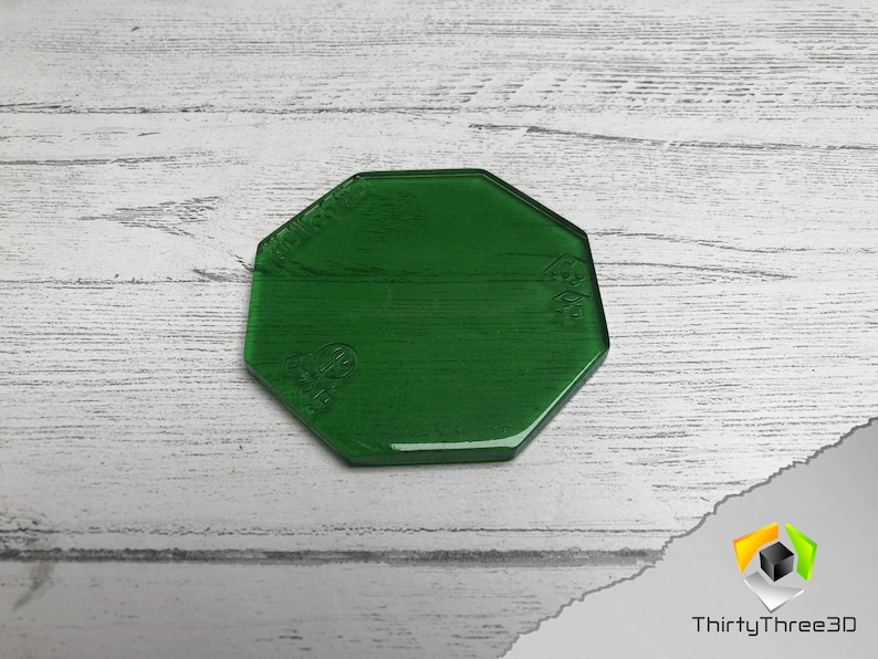 May include: A green octagonal acrylic base for miniature gaming. The base is translucent and has a smooth, glossy finish.