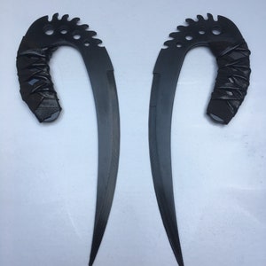 May include: Two black, curved, metal blades with a serrated edge and a black leather wrapped handle.
