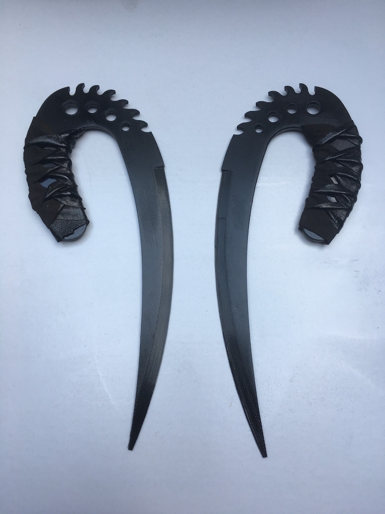 May include: Two black, curved, metal blades with a serrated edge and a black leather wrapped handle.