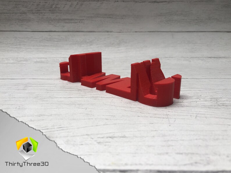 May include: A red 3D printed word "GAME" with each letter standing on its own. The letters are printed in a bold, blocky style.