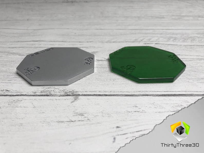 May include: Two octagonal gaming bases, one silver and one green. The bases are made of plastic and have a smooth, flat surface. They are designed for use with miniature figures.