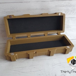 May include: An open tan plastic storage case with a black foam interior. The case has a latch on the front and a handle on the top.