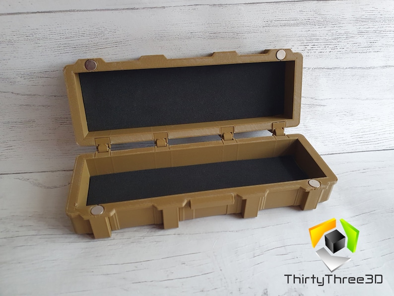 May include: An open tan plastic storage case with a black foam interior. The case has a latch on the front and a handle on the top.